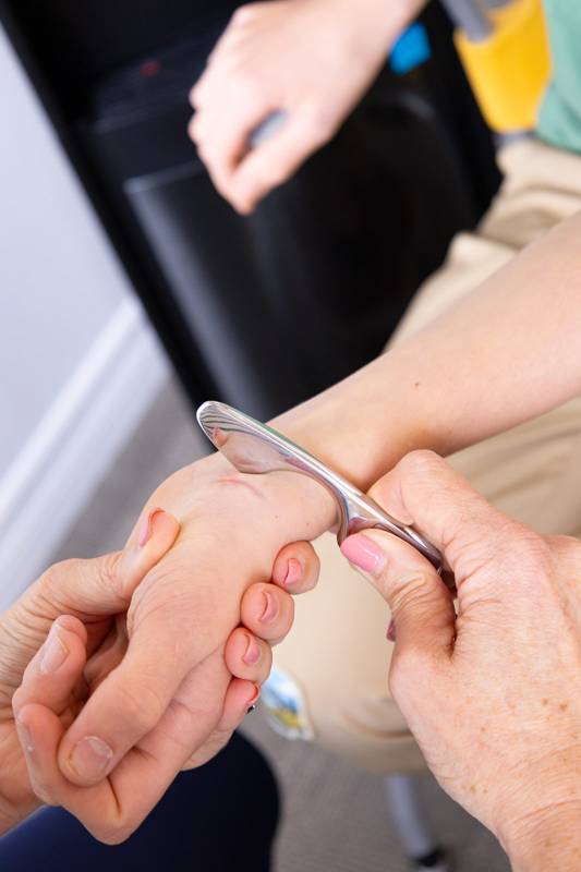 A Graston instrument used along a patient’s wrist and forearm