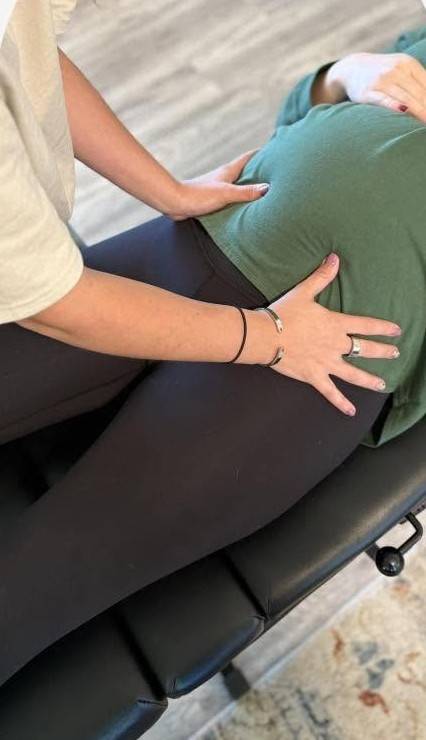 A chiropractor gently treating a pregnant patient lying on her side