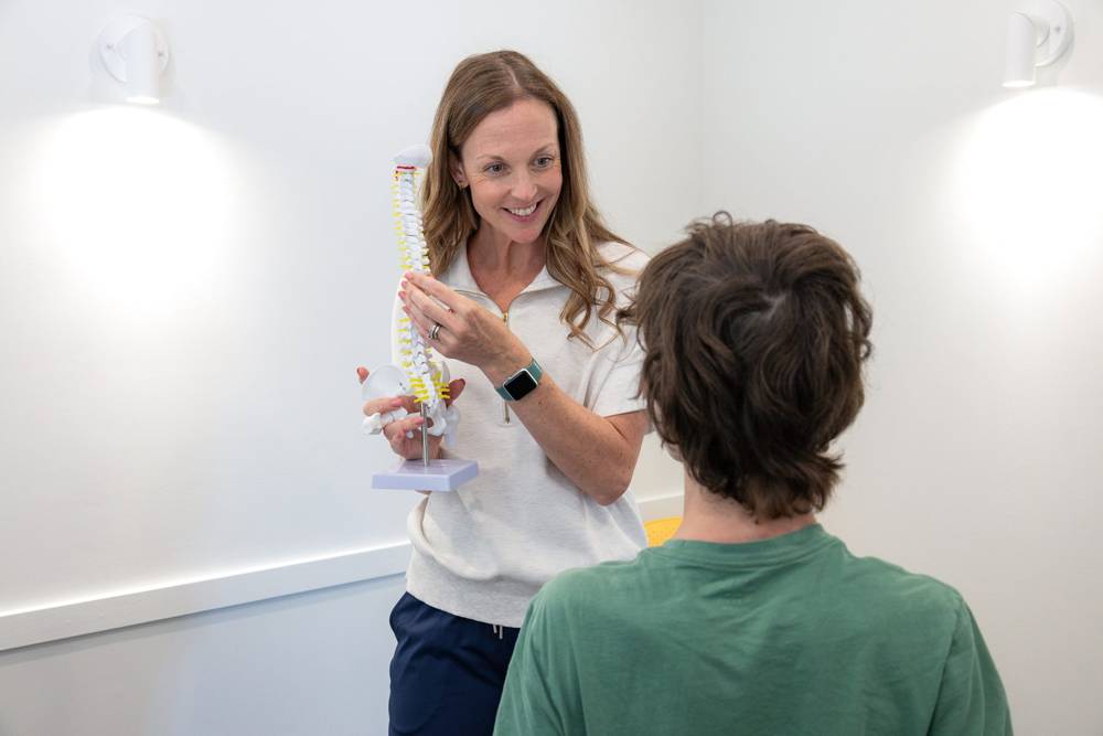 A chiropractor explaining the spine to a patient using a model